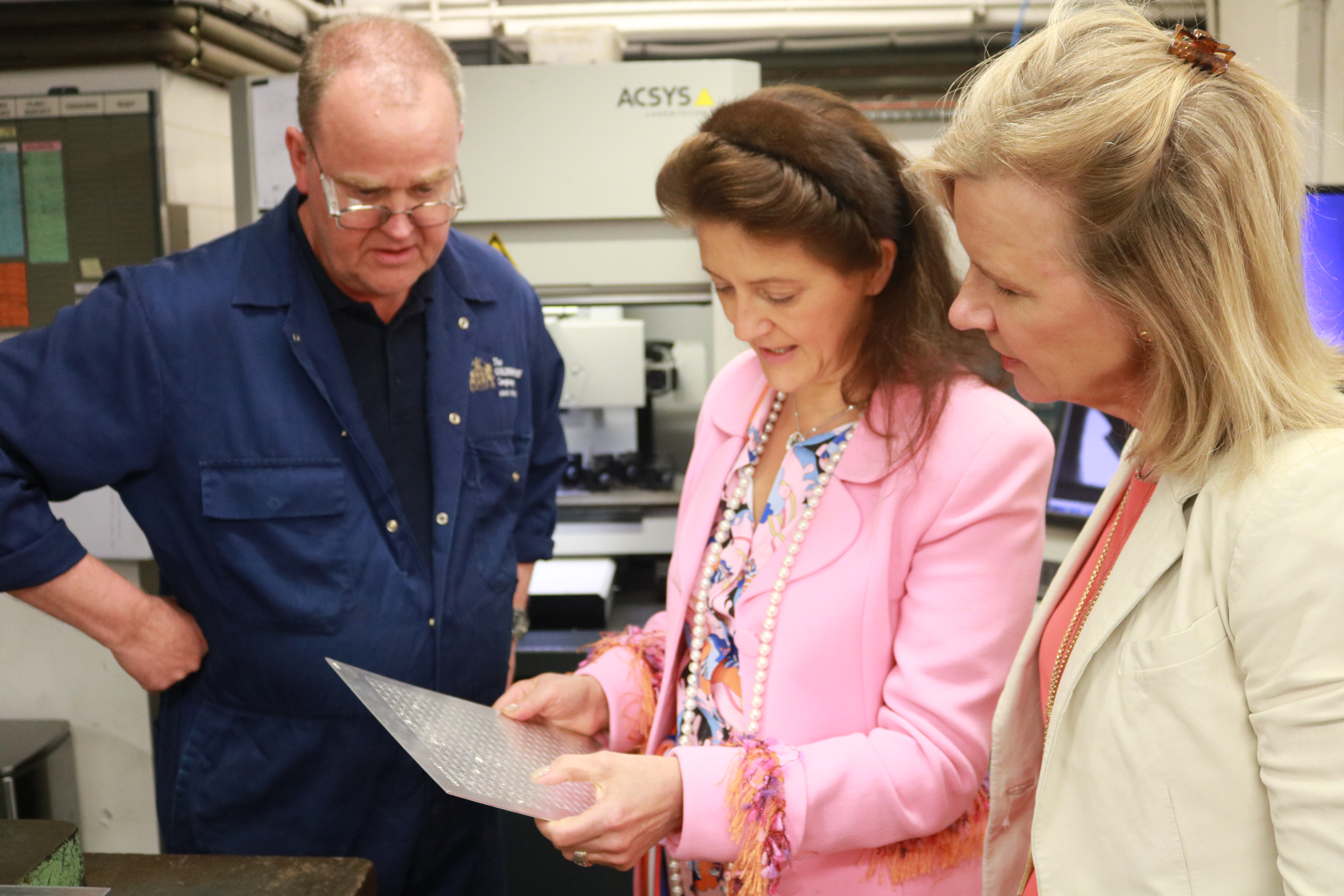 Cassandra Goad, and Vicky Broakes examine marking plates in the workshop with Pat.